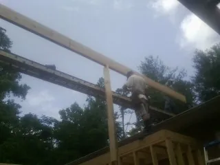 Carpenter setting a ridge beam over a new addition frame — Ice Dam Removal by Roofing Brothers in Beemer