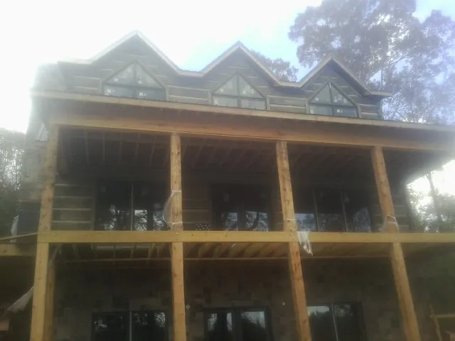 Dormers and porch framing on a large log home under construction — Roof Coating work by our crew in Beemer
