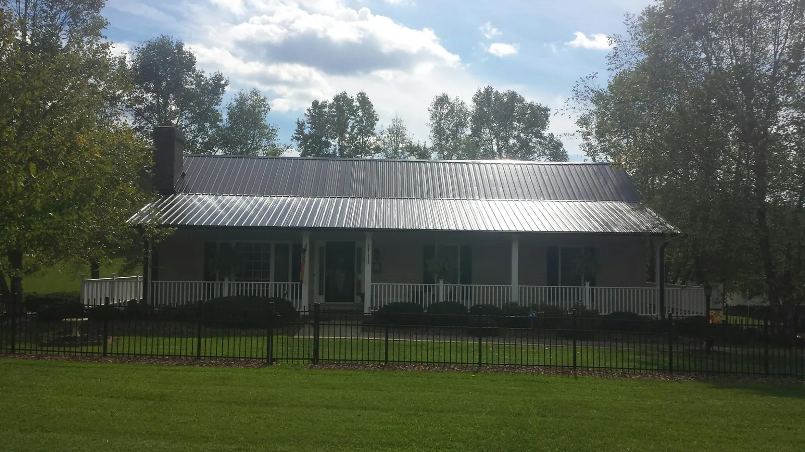 Gray metal roof on a brick ranch with a full width front porch — Gutter Guard Installation work by our crew in Beemer
