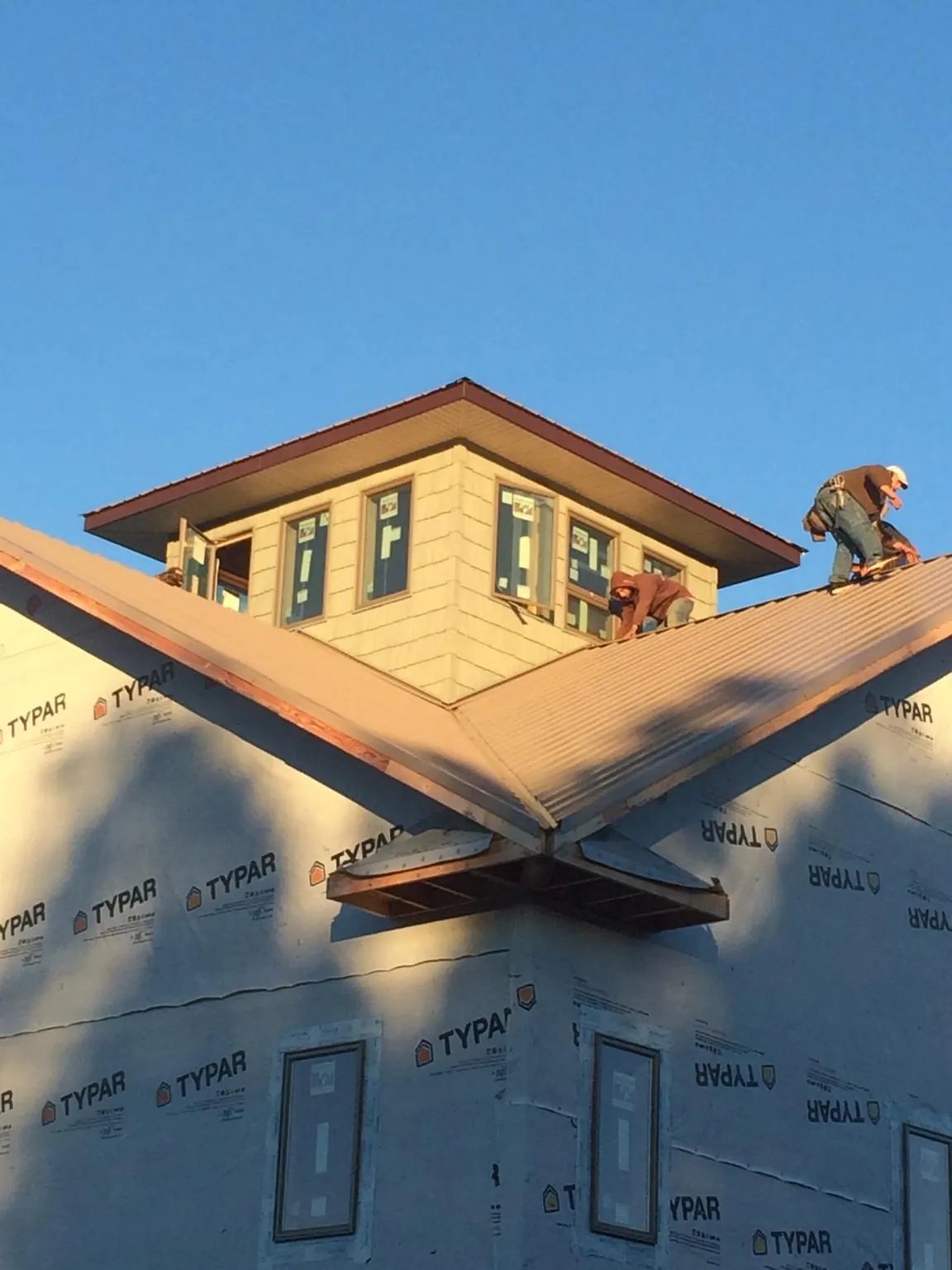 Roofers working around a rooftop cupola on a new metal roof at sunset — Roof Waterproofing in Beemer by Roofing Brothers